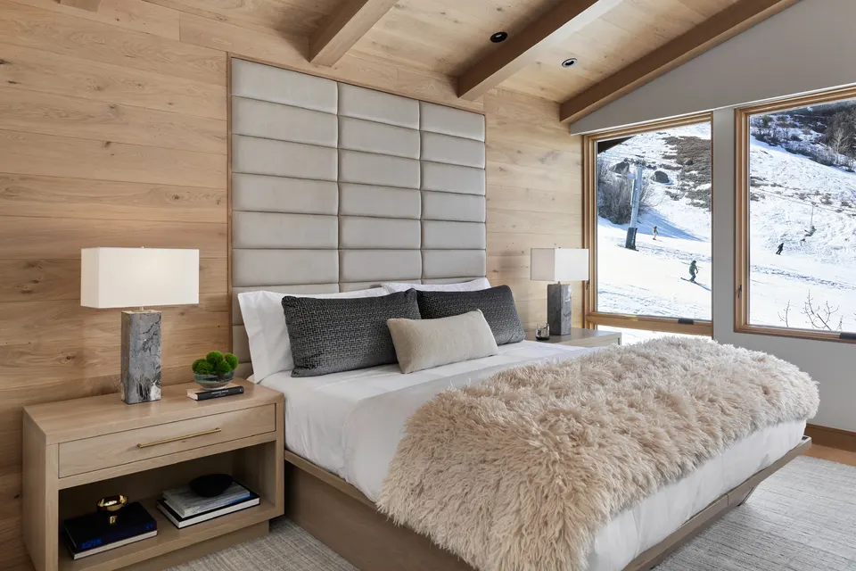 Primary bedroom with pale white oak floor and snowy mountain views