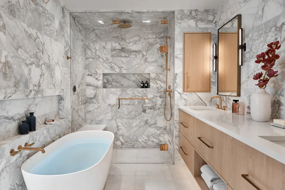 Marble bathroom with a freestanding tub and pale white oak floor