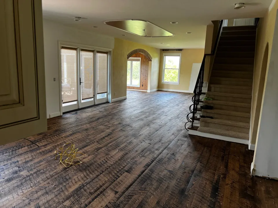 Worn, distressed hardwood floor in an empty room before refinishing