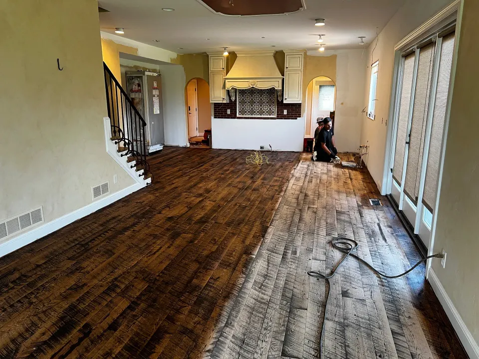 Worker applying stain to a sanded hardwood floor