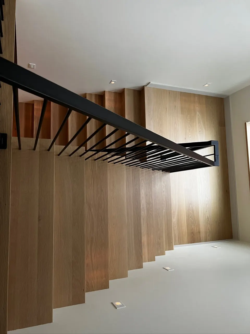 Light oak floating staircase with a black railing