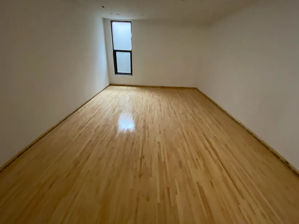 Freshly finished maple floor with a glossy sheen in an empty room