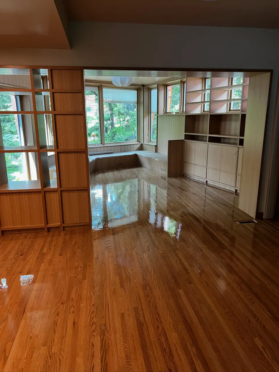 Freshly finished oak floor with a glossy coat in a room with white built-in cabinetry.