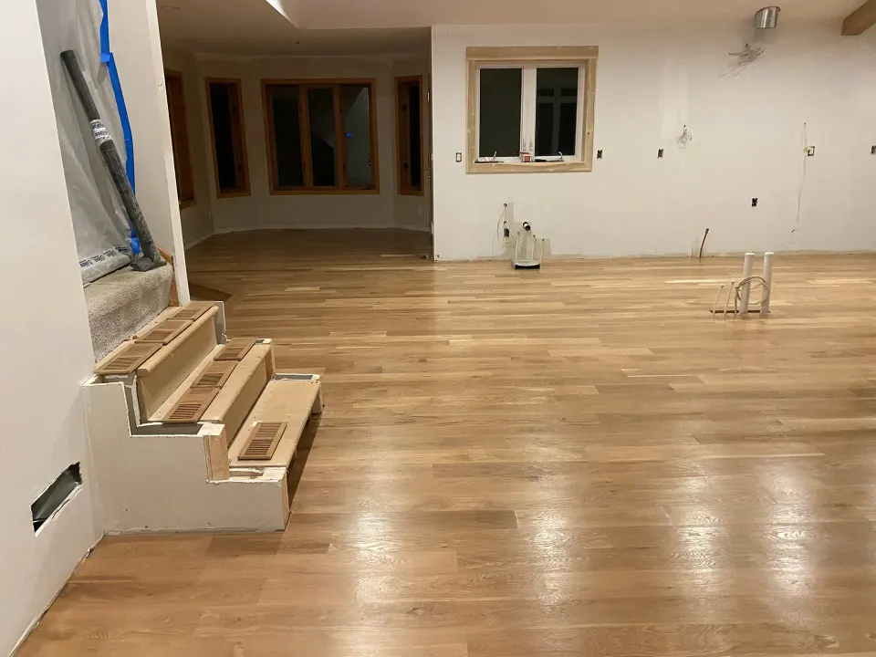 Natural oak plank flooring partway through installation in a large open room