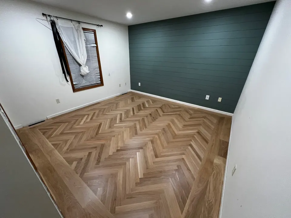 Light oak herringbone in a bedroom with a teal wall