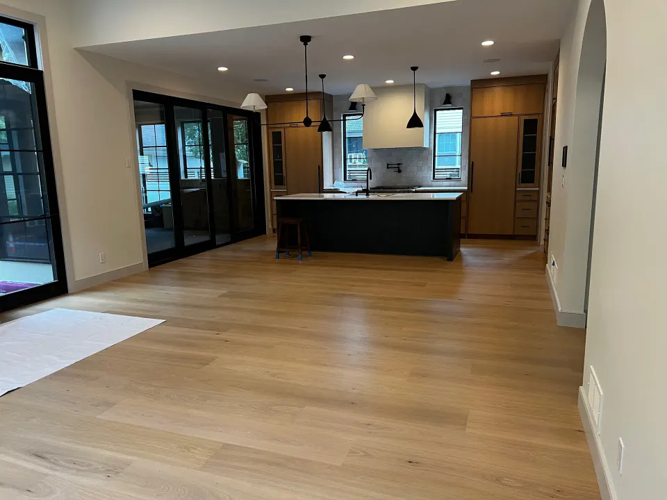 Wide plank light oak flooring in a kitchen with a dark island and white cabinets