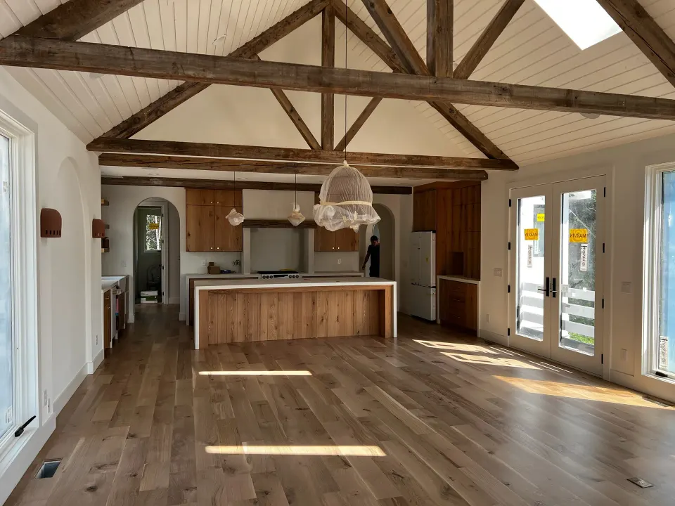 Open kitchen with rustic oak plank flooring under exposed ceiling beams