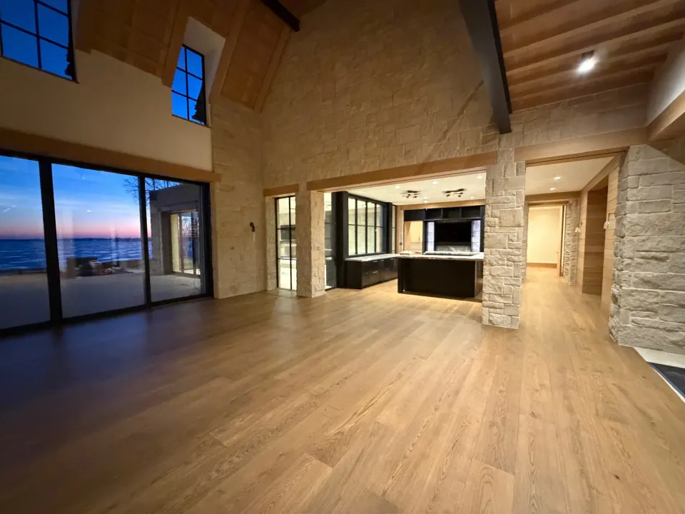 Light oak through an open living room and kitchen at dusk
