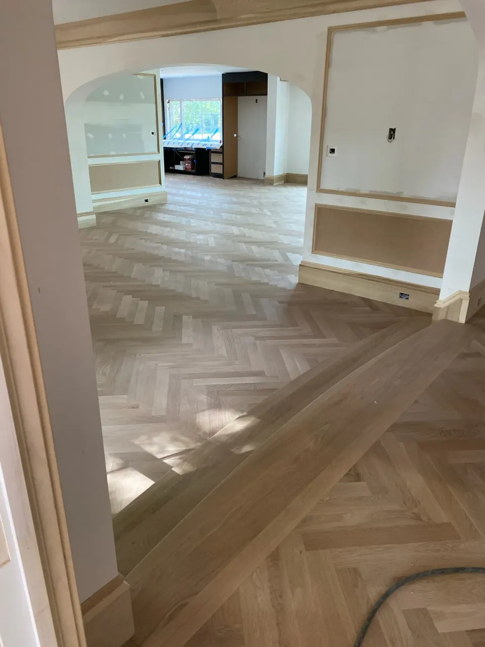 Unfinished herringbone floor with a straight board border fitted to arched doorways