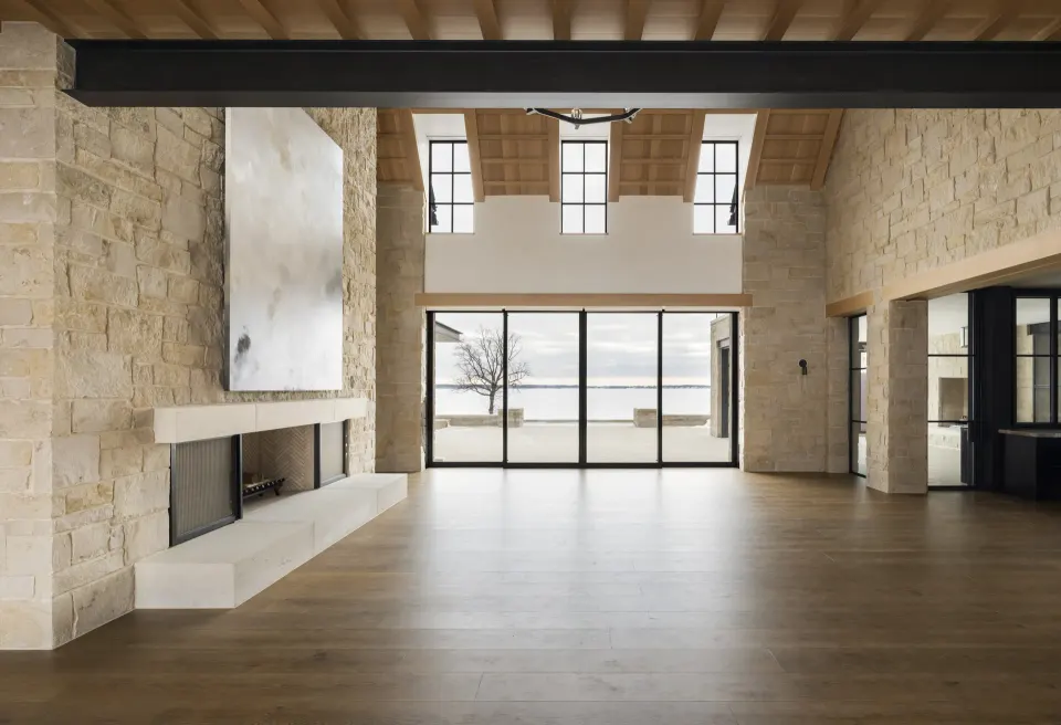 Wide-plank white oak great room with a stone fireplace wall and lake view