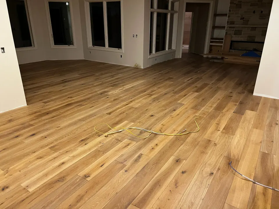 Wide plank oak flooring being installed across an open concept main floor