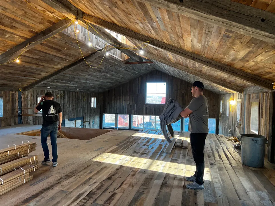 Alpine Hardwood crew laying reclaimed plank inside a timber barn